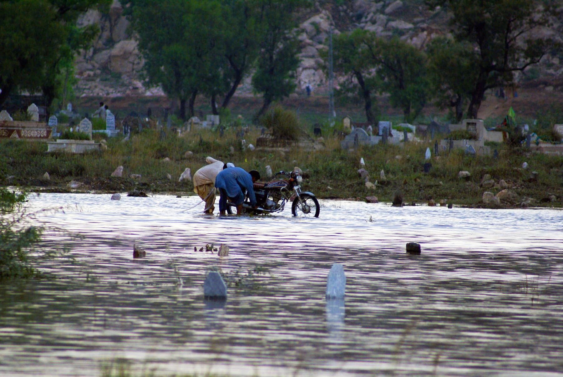 Men recover a motorcycle stuck in water during severe flooding. Pakistan, 2010.