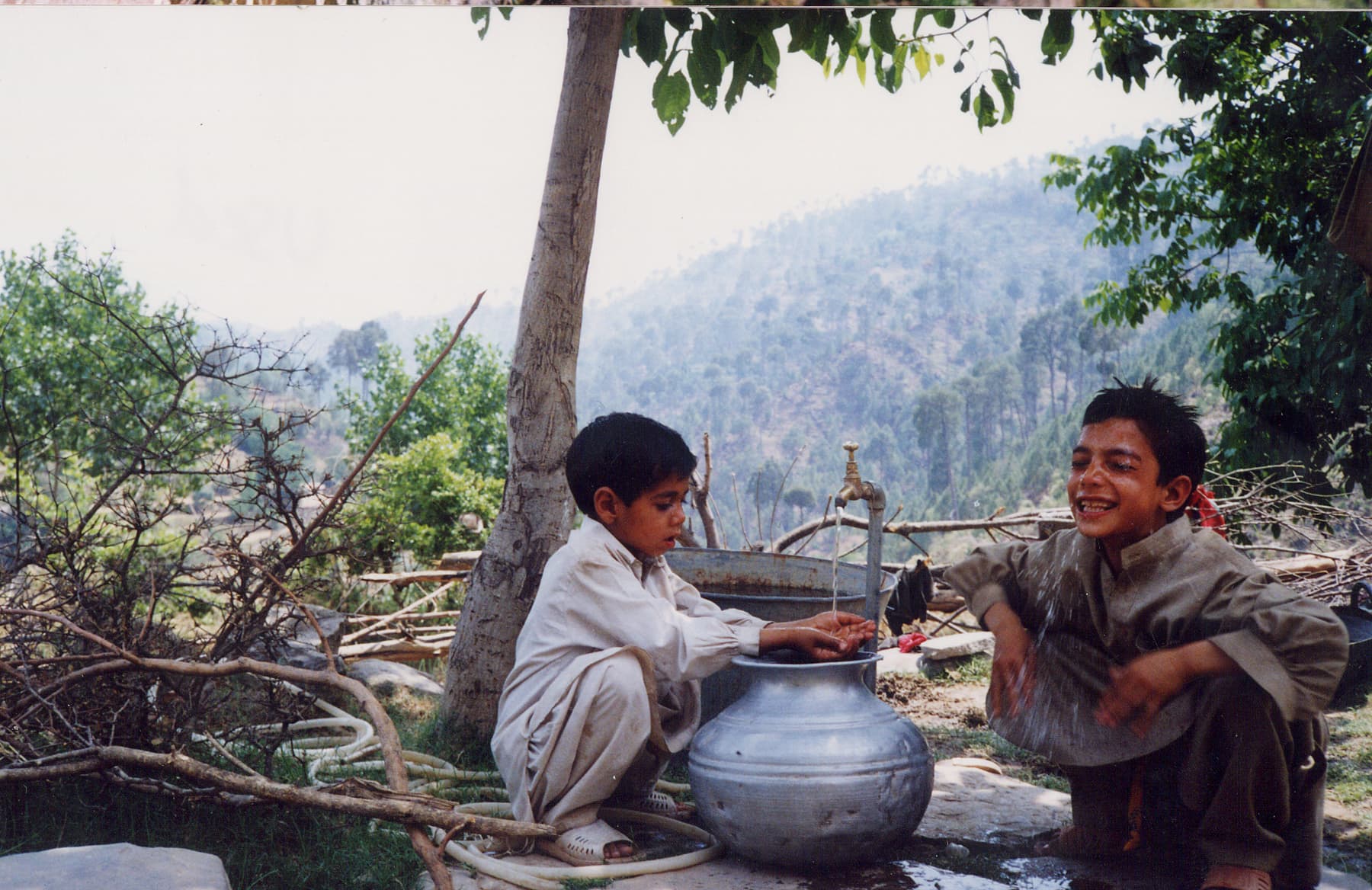 Young boys collect water from water tap installed by Islamic Relief in Kashmir. Pakistan, 2012.