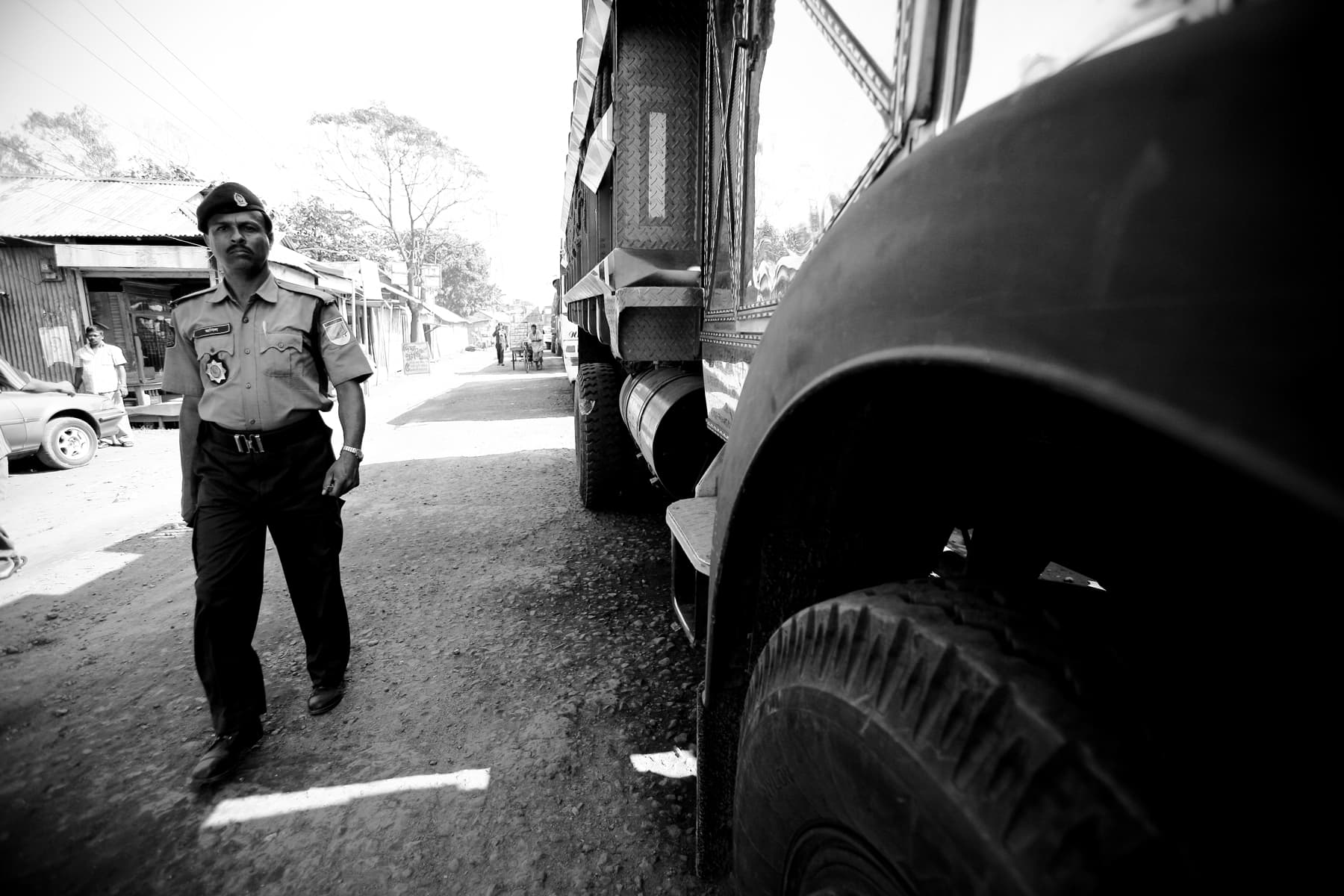 A police officer supervises a convoy of aid trucks post cyclone. Bangladesh, 2012.
