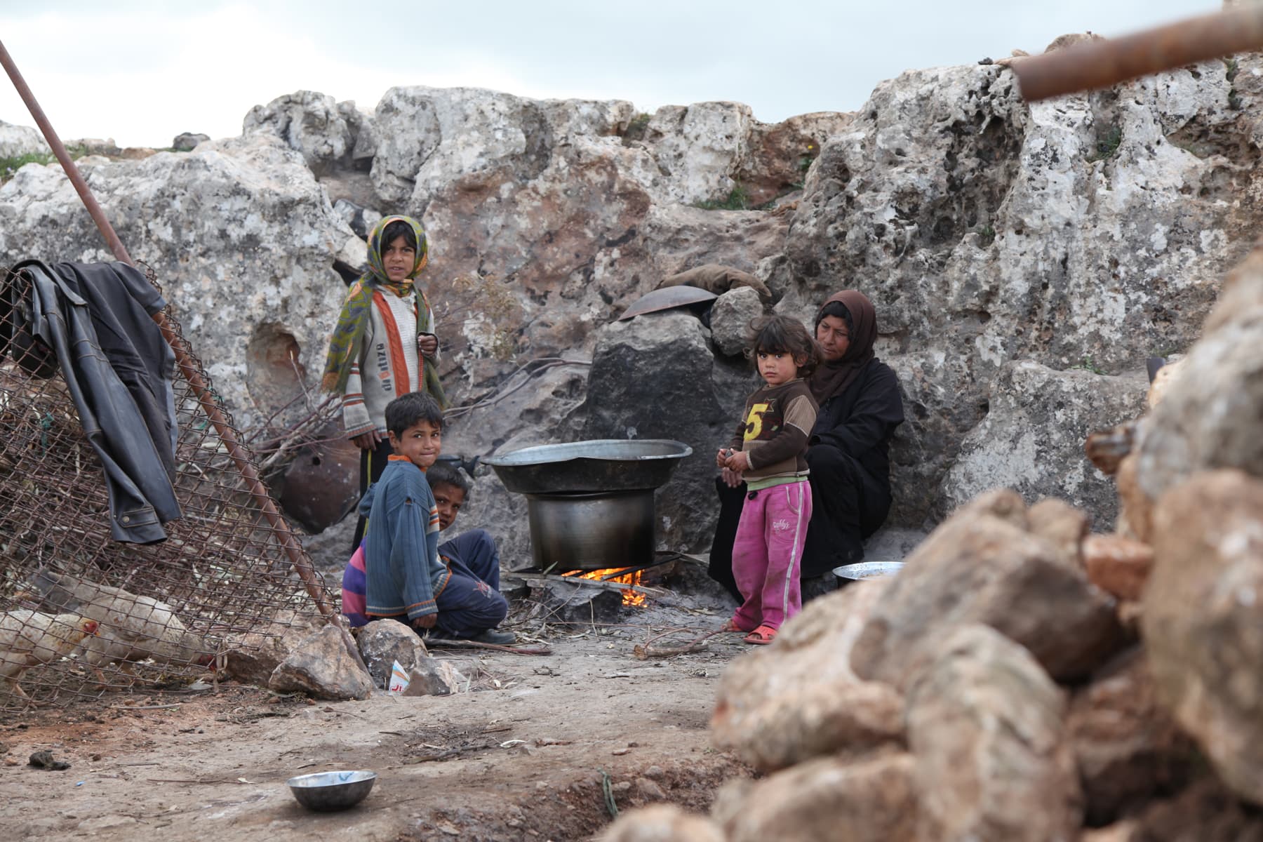 An internally displaced family gather around a make shift stove at a temporary camp for internally displaced. Syria, 2013.