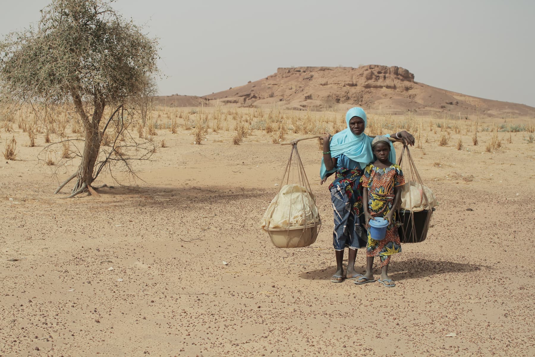 A mother and daughter carrying buckets of water to their village. Niger, 2012.