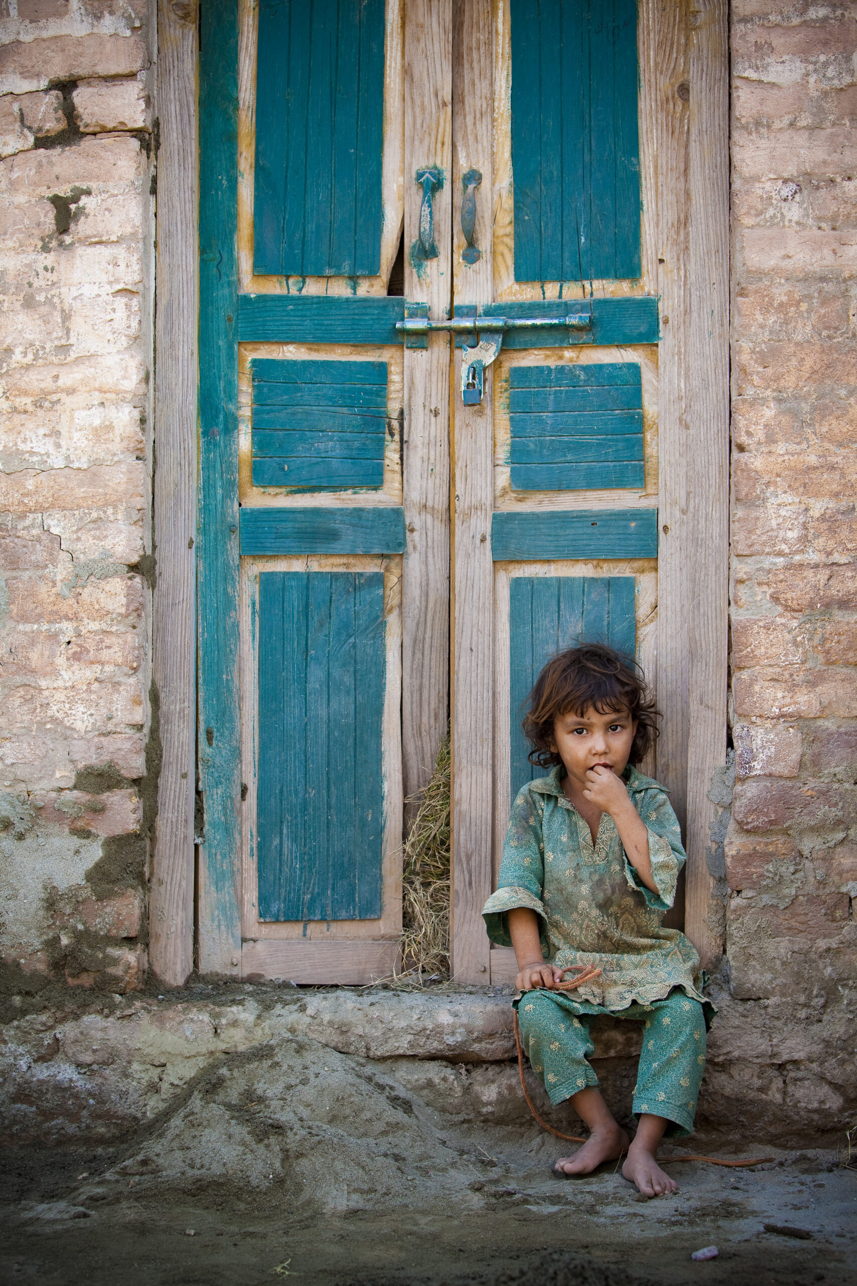 A little girl sits in a doorway, holding her skipping rope following the severe flooding. Pakistan, 2010.