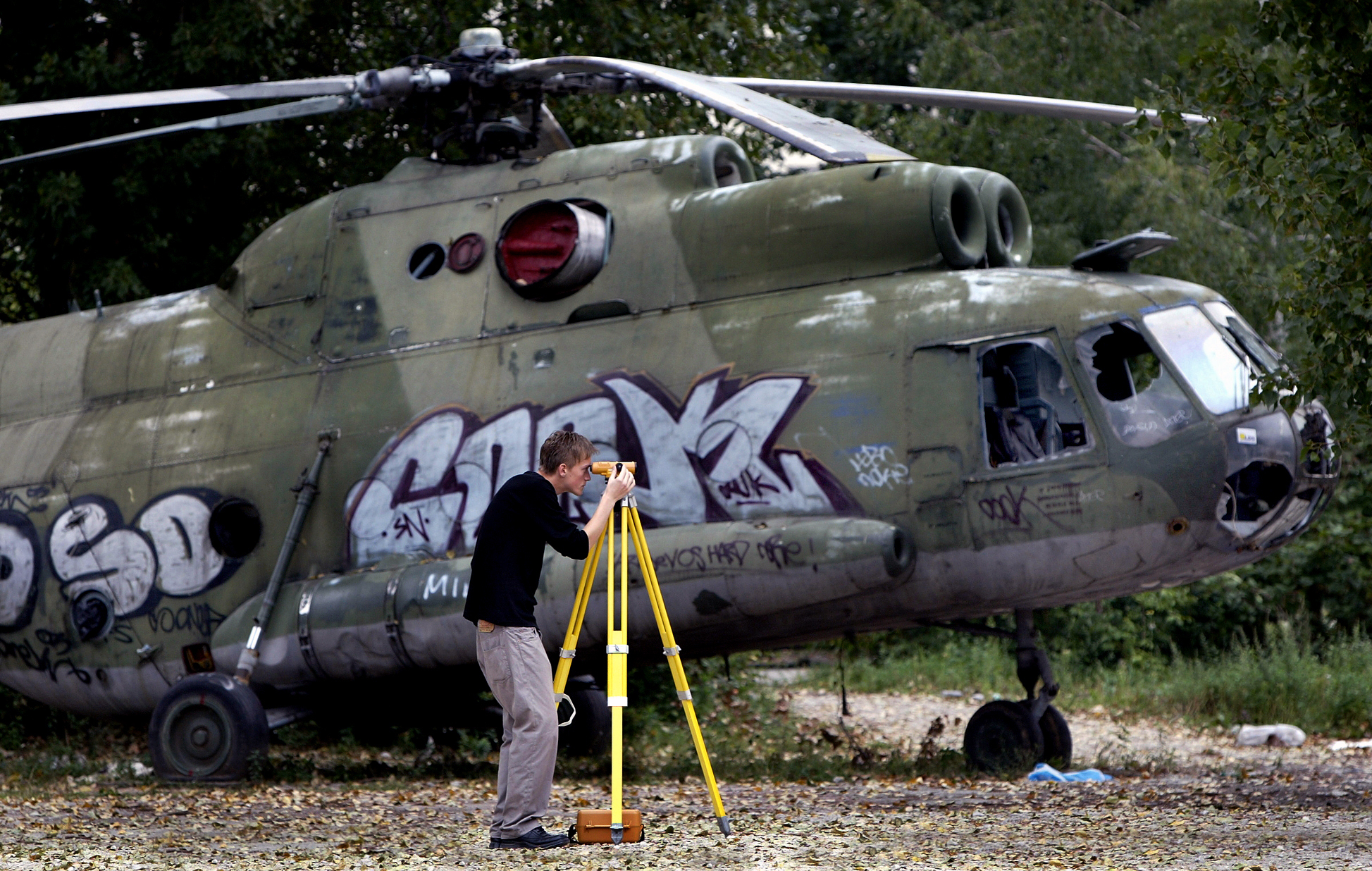 A man surveys the area next to a damaged military helicopter. Bosnia and Herzegovina, 2004.