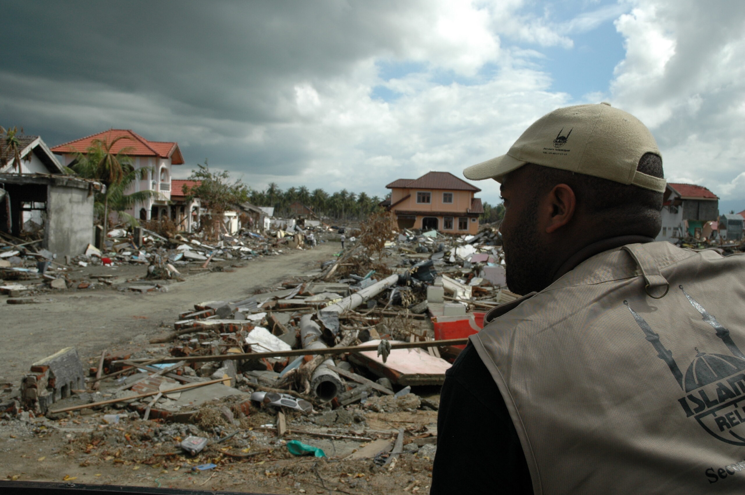 An Islamic Relief staff member looks at destruction caused by the 2004 Indian Ocean earthquake and tsunami. Indonesia, 2005.