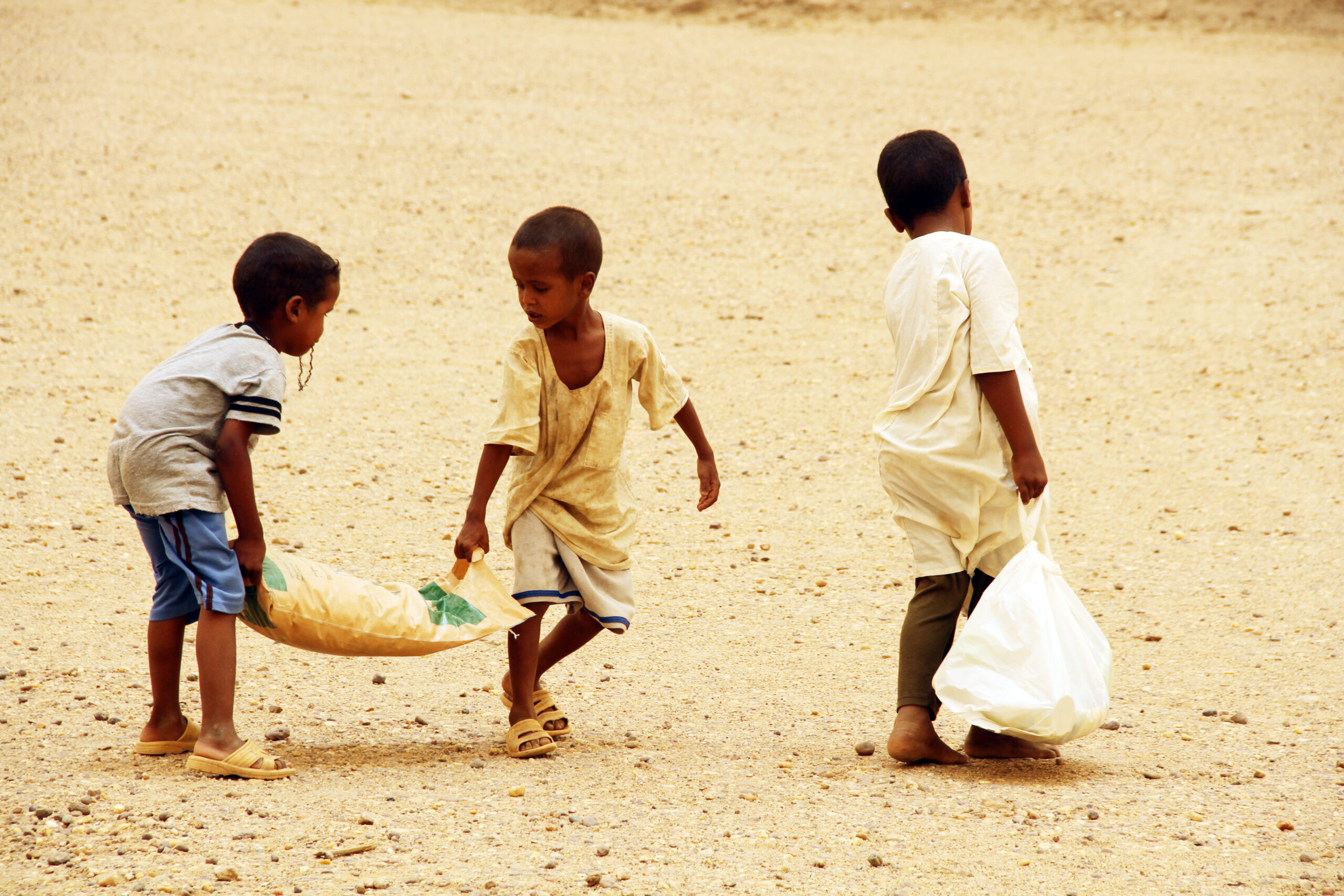Young boys carry home food from an Islamic Relief Ramadan distribution. Sudan, 2014.