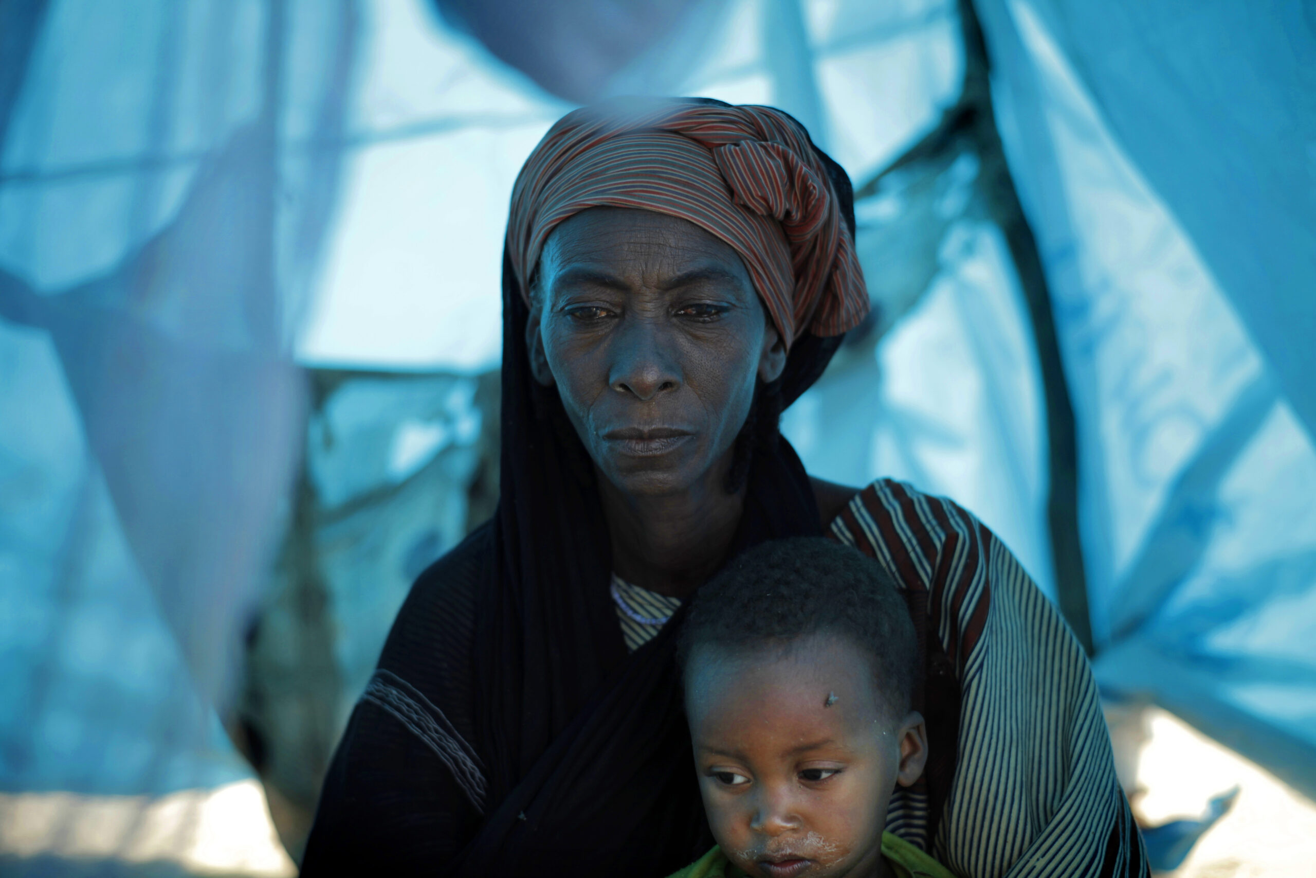 A refugee mother and her child shelter from the sun in a tent. Niger, 2012.