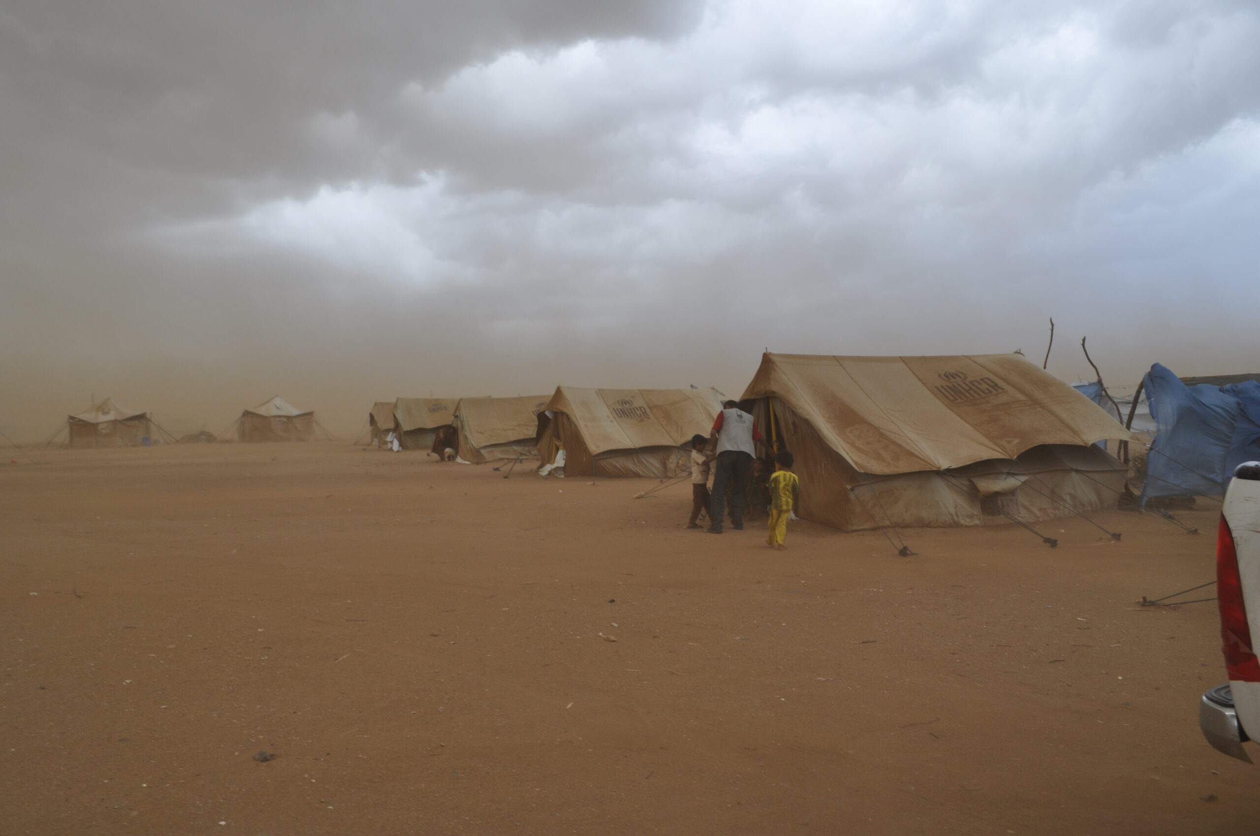 Islamic Relief staff help children as a sandstorm closes in on tents housing displaced people in Yemen. Yemen, 2010.