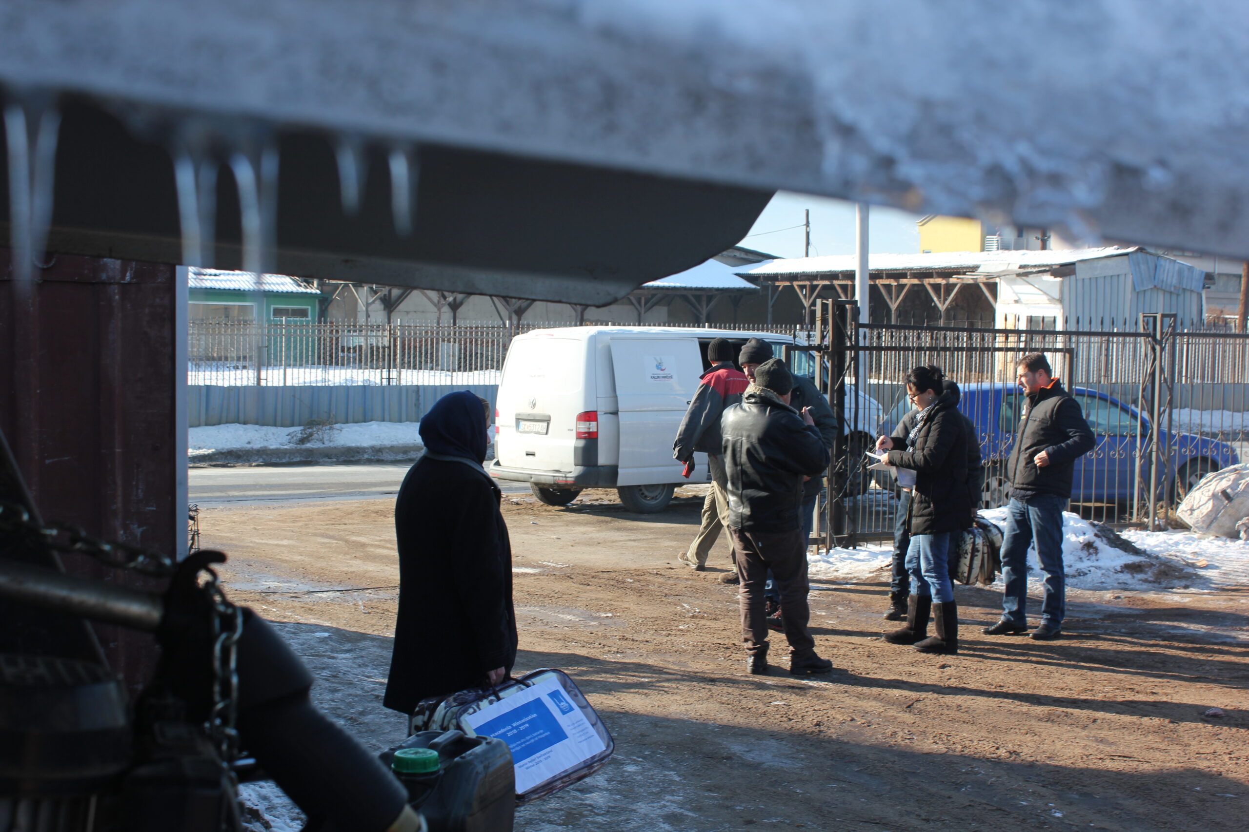 Snow and icicles frame Islamic Relief staff preparing to distribute firewood and blankets to keep families warm in winter. North Macedonia, 2014.