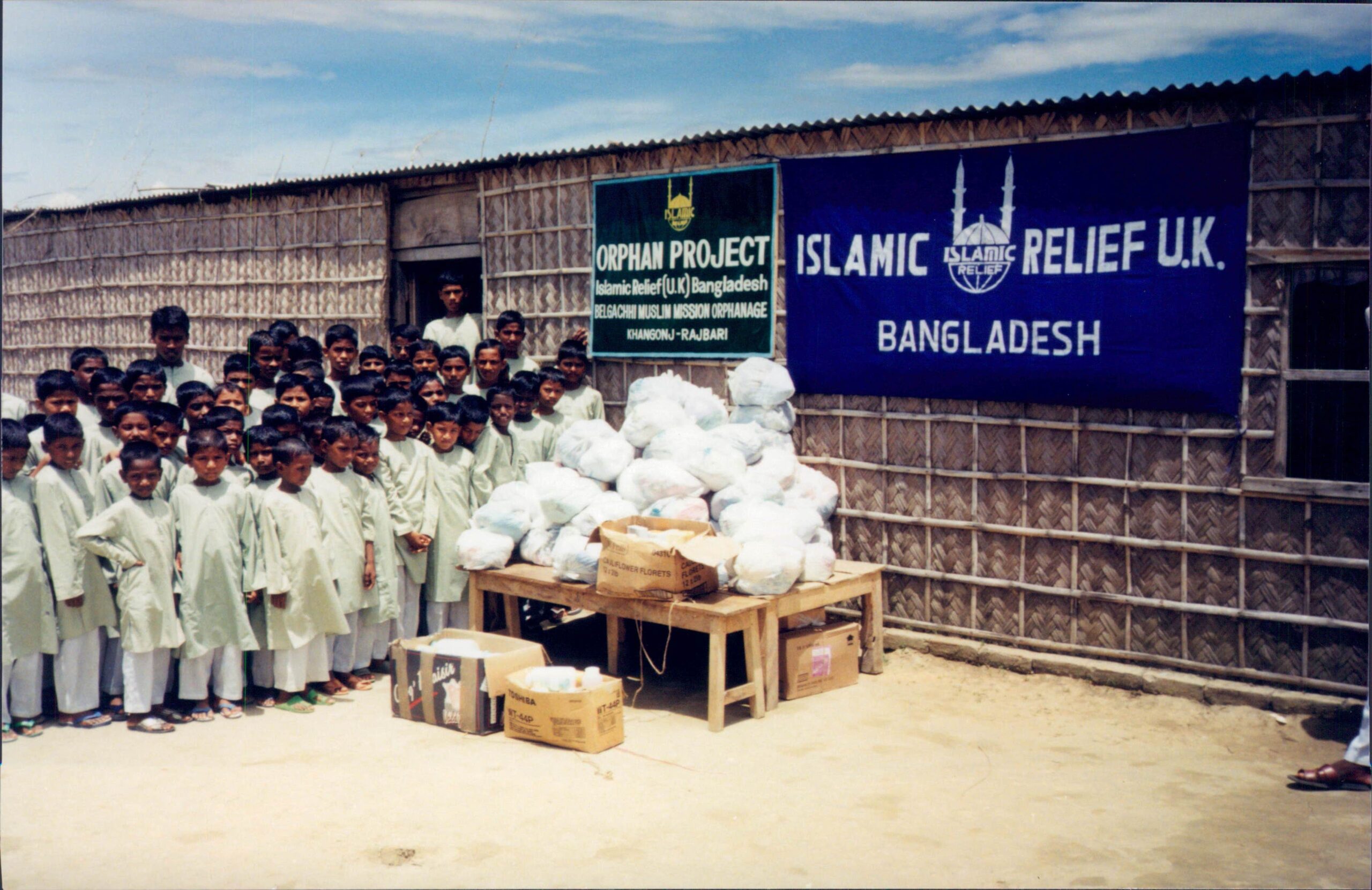 Orphaned children stand next to aid items at an orphanage in Rajbari. Bangladesh, 1996.